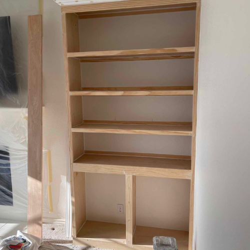 Wooden bookshelf built into a wall, with four shelves and two lower compartments.