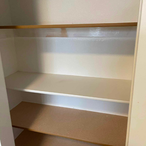 Empty white closet with three shelves and a clothing rod.