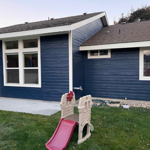 Blue house with white trim and windows, a slide in the yard.