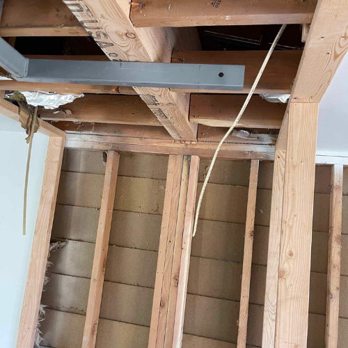 Construction site: exposed ceiling joists and wall studs with electrical wiring.