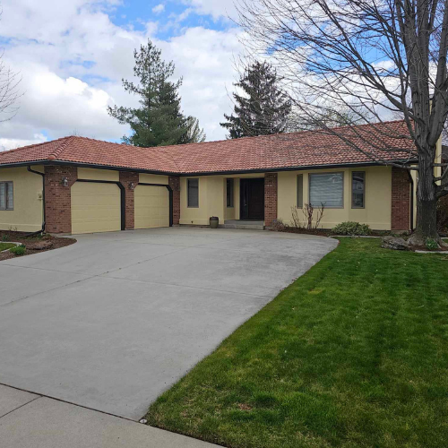 Yellow house with brick accents, terracotta roof, and concrete driveway.