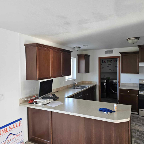 Kitchen with dark brown cabinets, light countertops, and laundry room access.