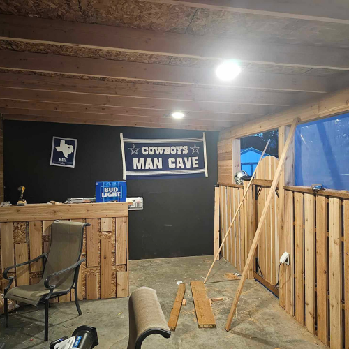 Man cave under construction with Cowboys banner and wooden features.