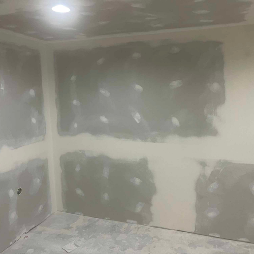 Interior room with gray-patched drywall walls and ceiling, ready for finishing.