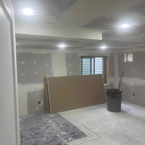 Room under construction with drywall and recessed lights.
