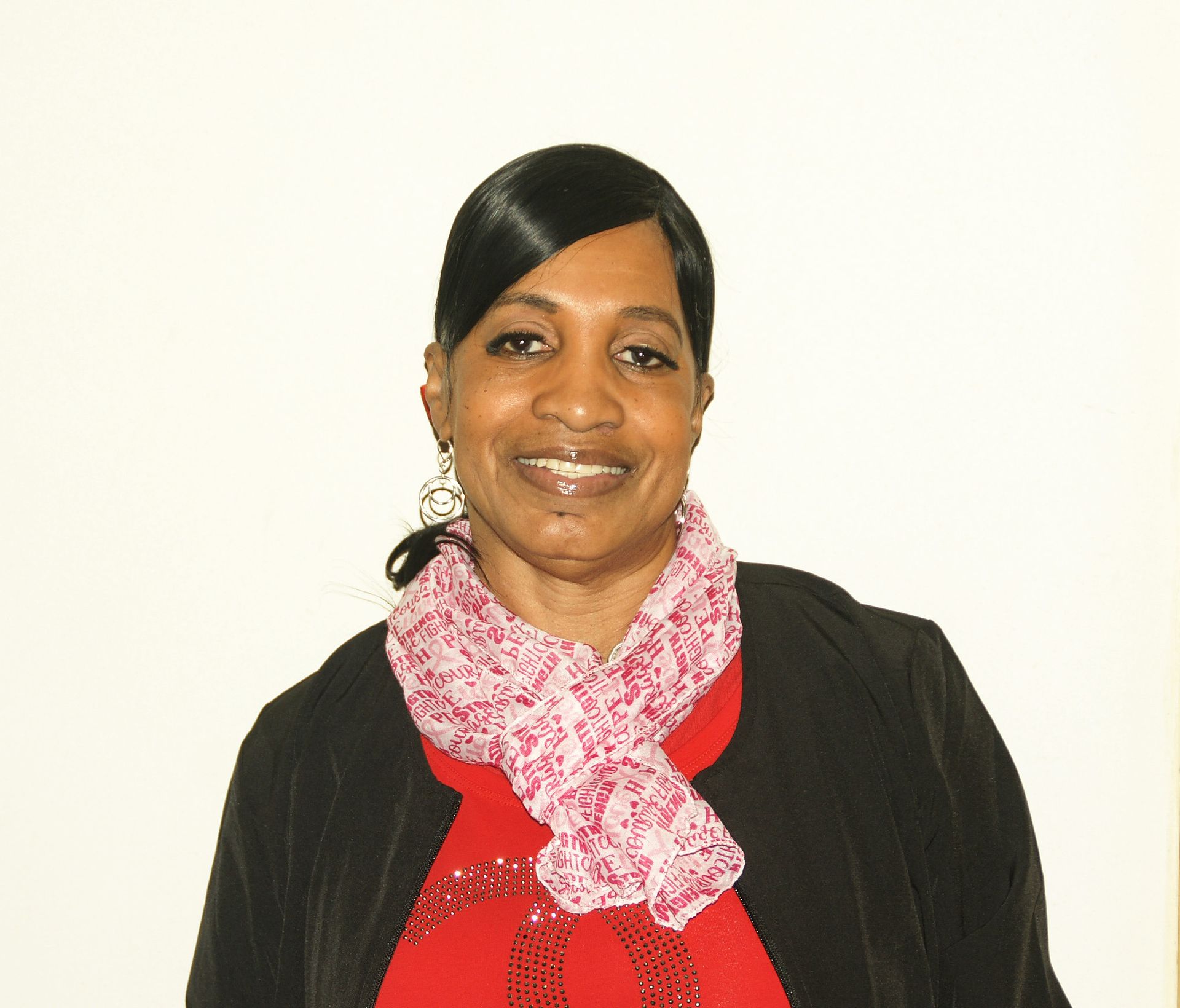 A woman wearing a green polo shirt and earrings is smiling for the camera.