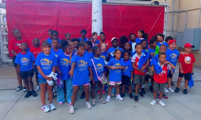 A group of children wearing school clothing pose and smile for a group photo