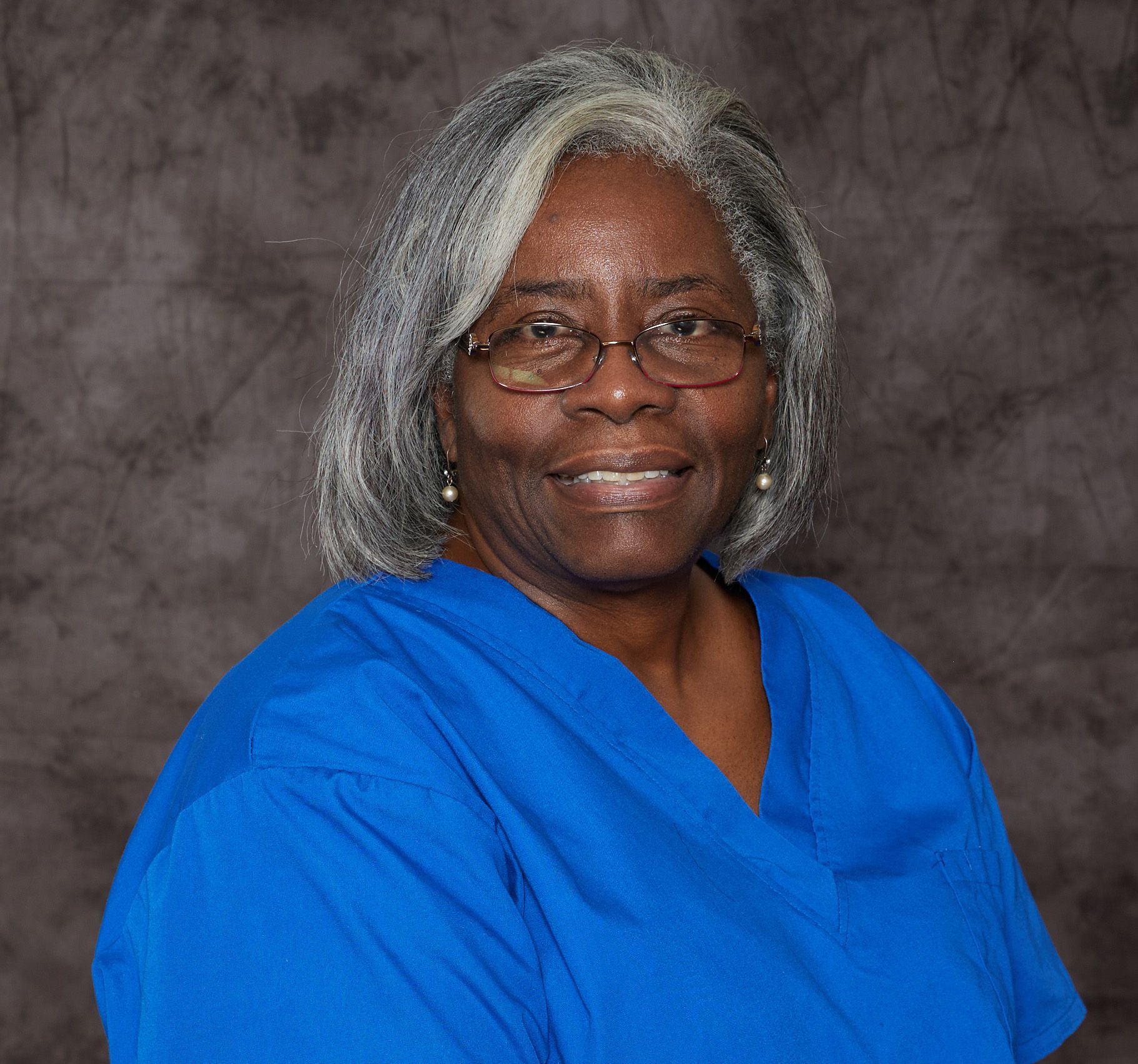 A woman in a purple shirt is smiling for the camera.