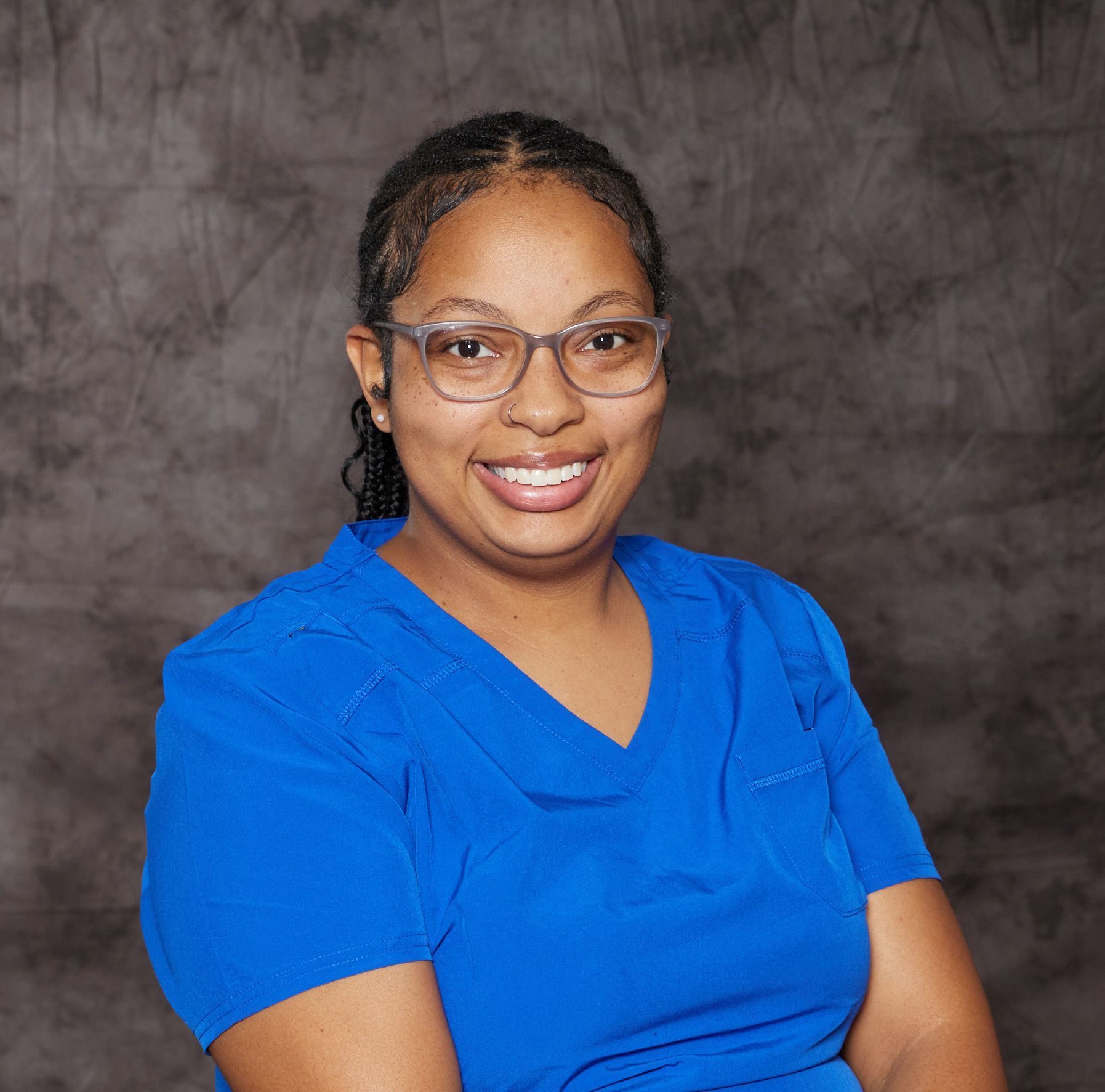 A woman with curly hair is smiling for the camera while wearing a white shirt.
