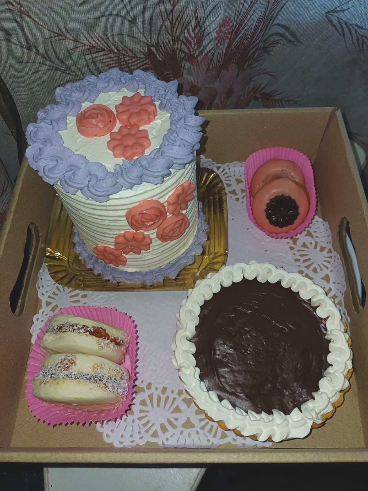 Bandeja con pastel, galletas y una tarta, todo decorado con glaseado y colocado sobre tapetes.