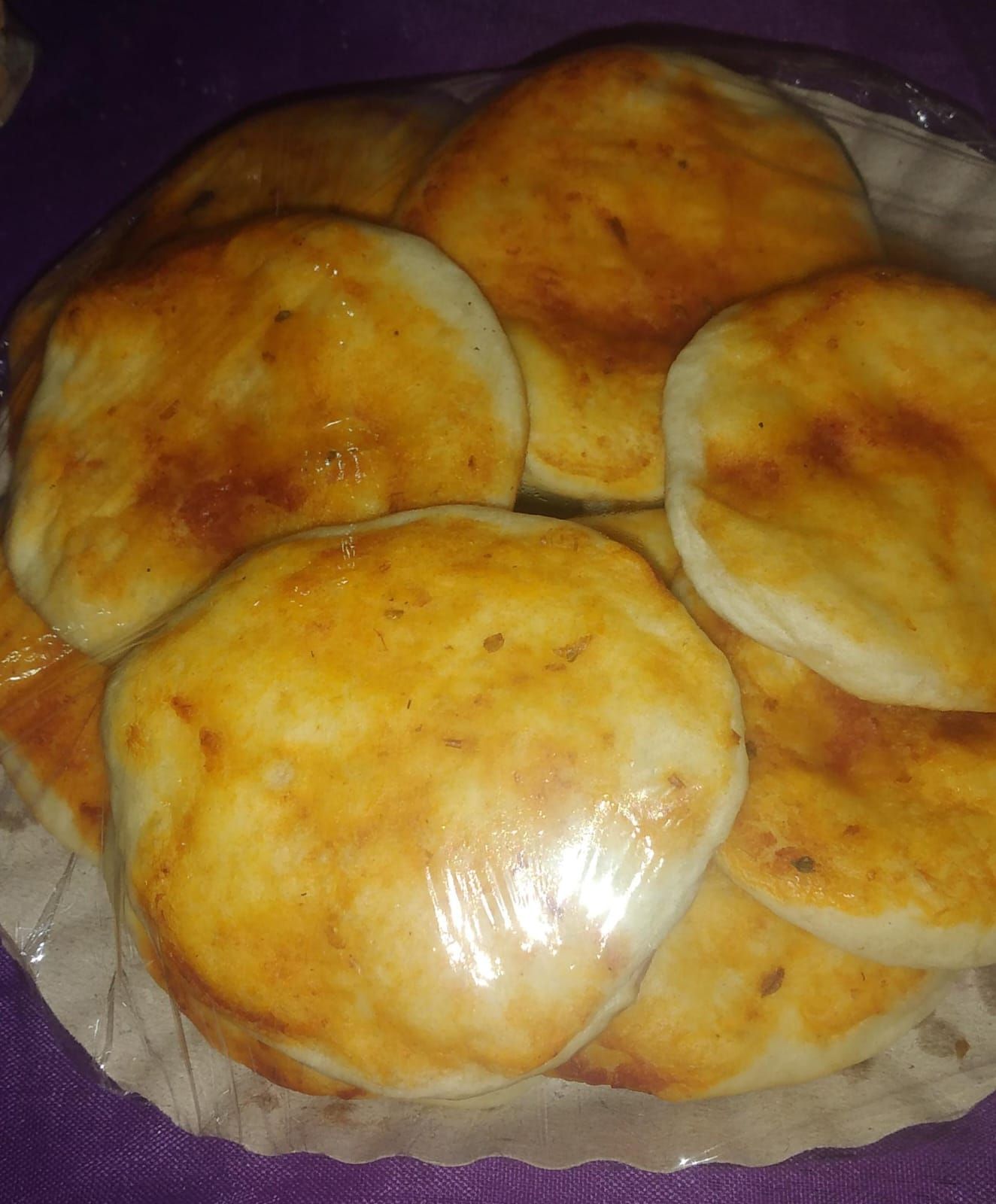 Pila de panes planos redondos de color marrón dorado en una canasta forrada de plástico.
