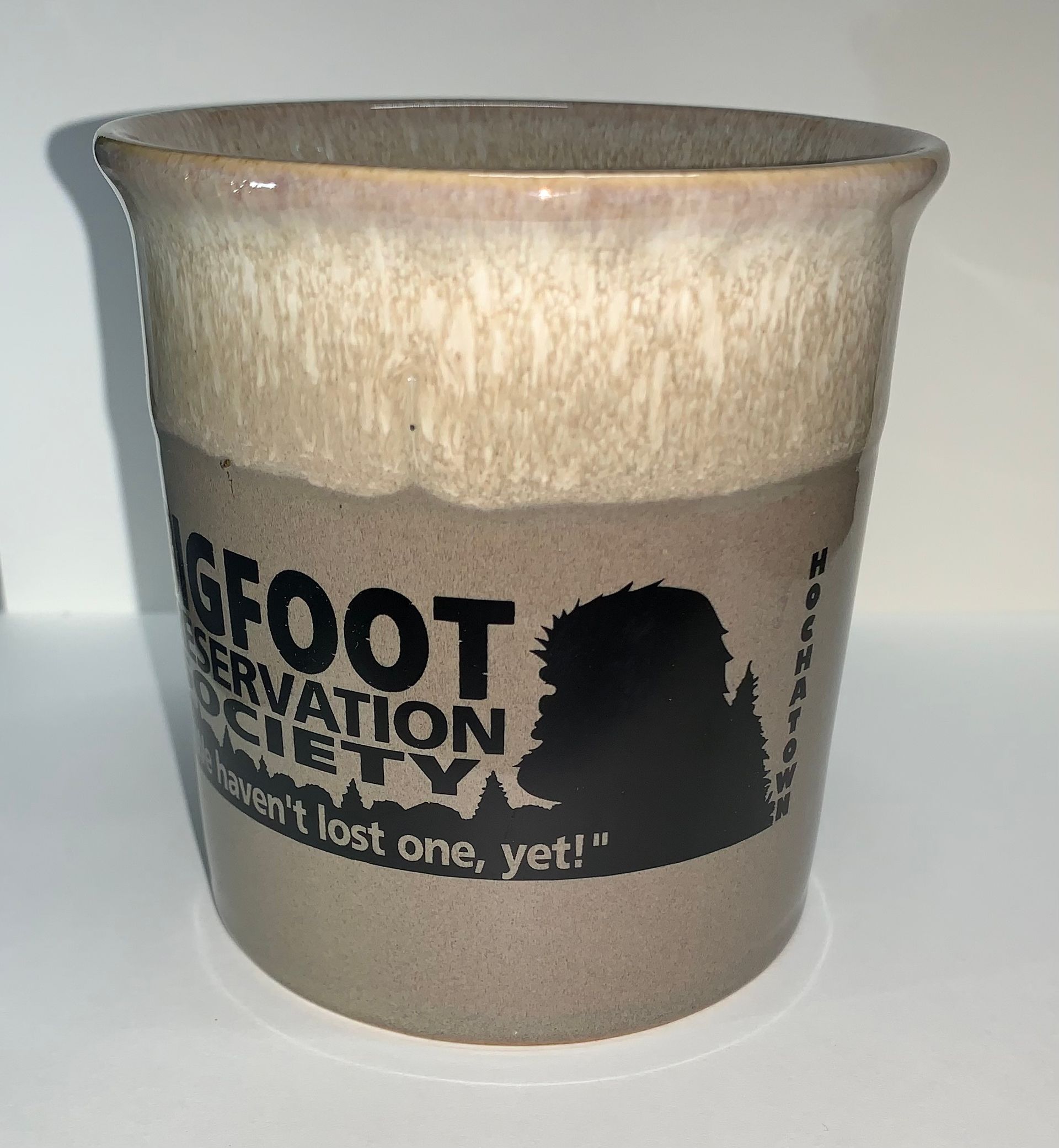 Ceramic mug with Bigfoot Preservation Society text in black on a beige background