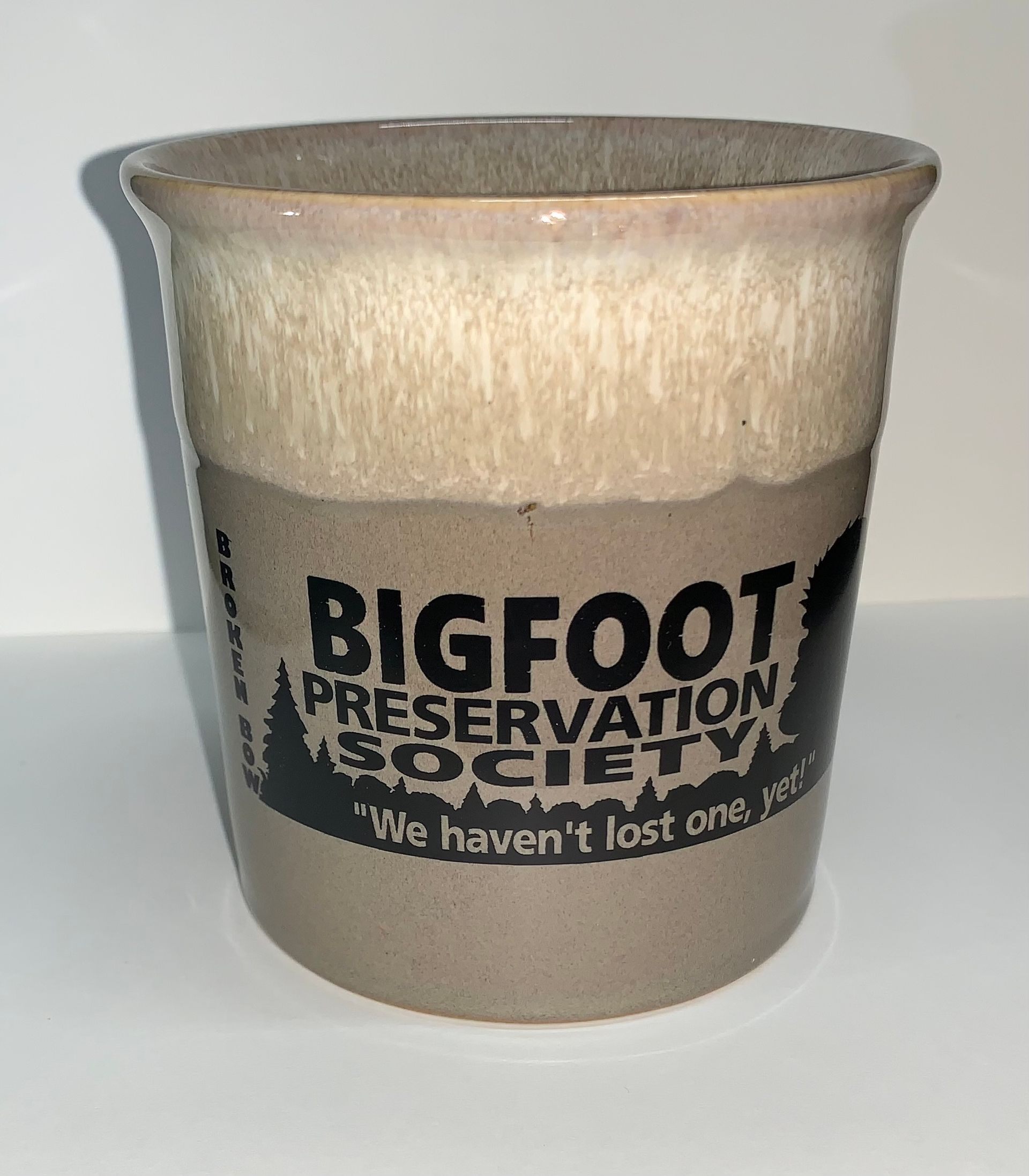 Ceramic cup with tan glaze and Bigfoot Preservation Society logo in black