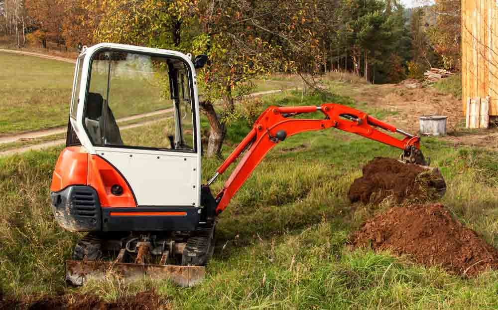 A small excavator on a grassy building site.