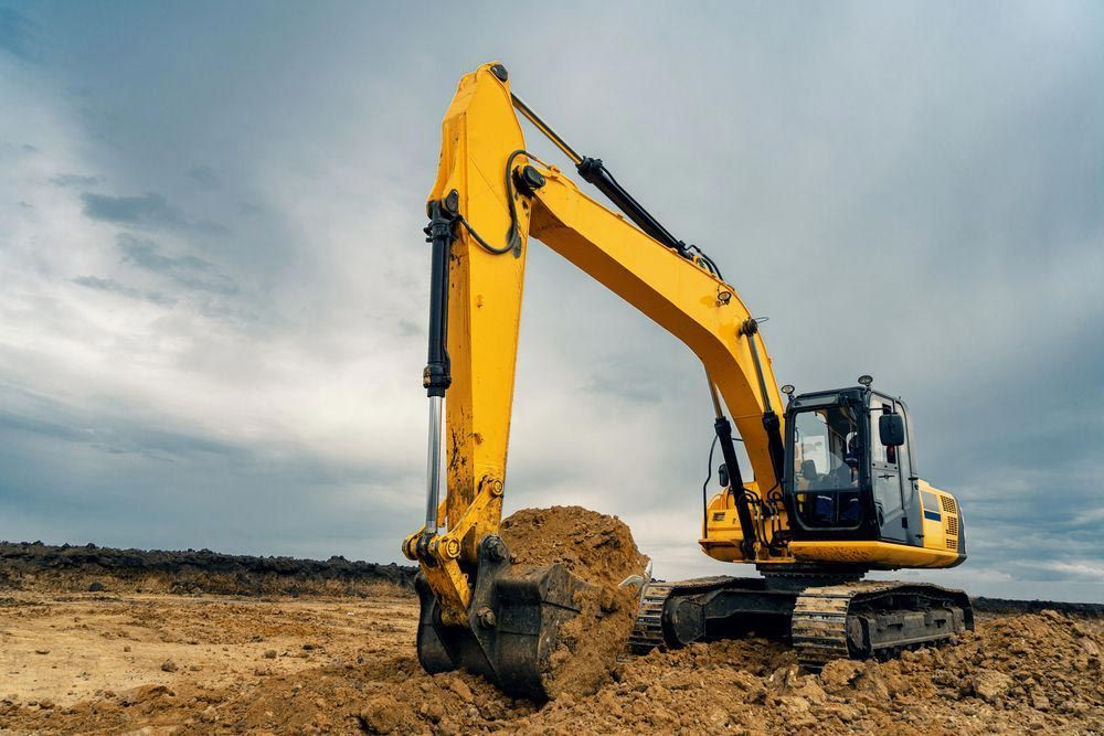Yellow Excavator In The Middle Of A Field — Rayment Excavations in Gladstone, QLD