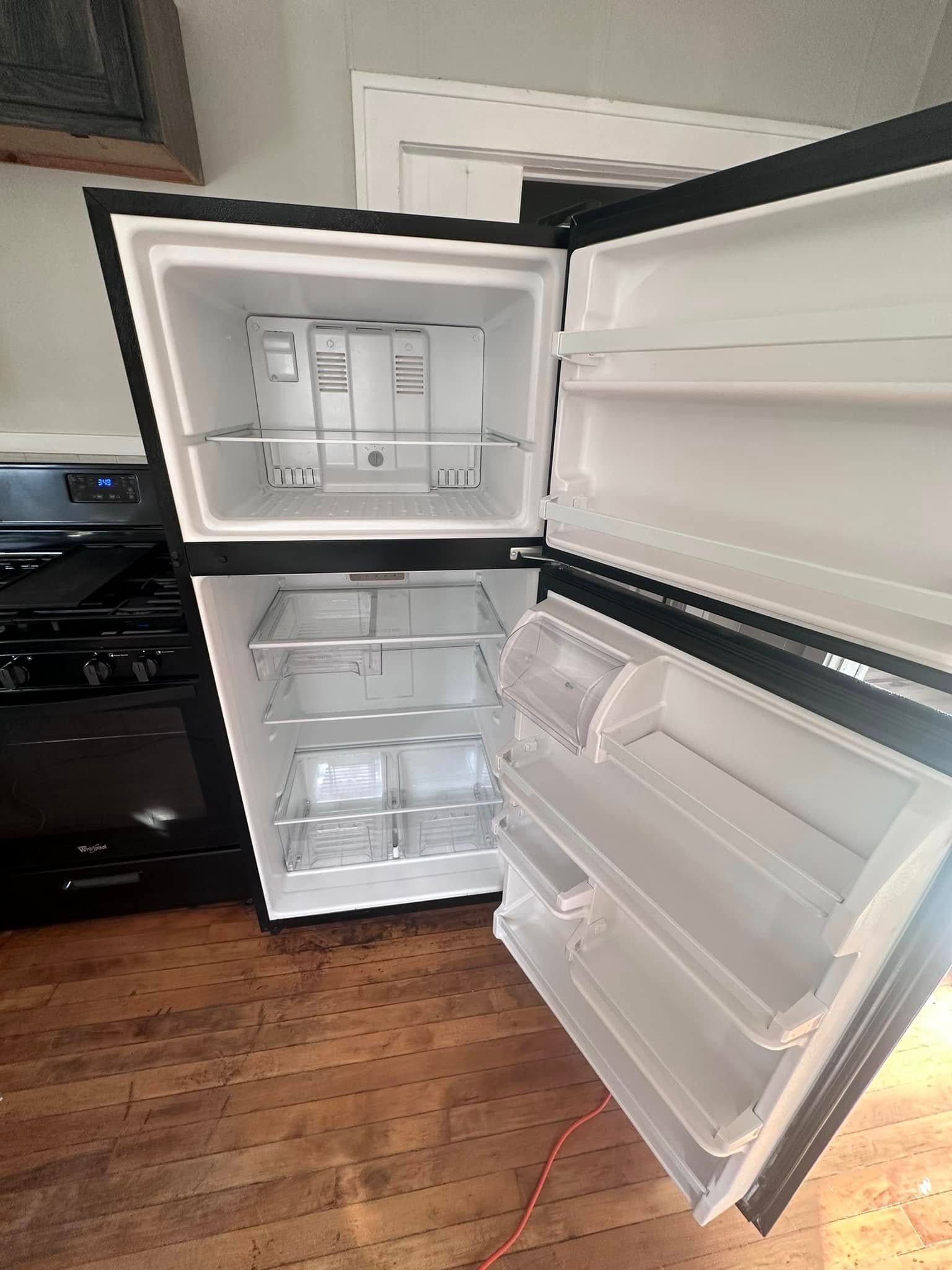 Black top freezer refrigerator with open doors, interior view.