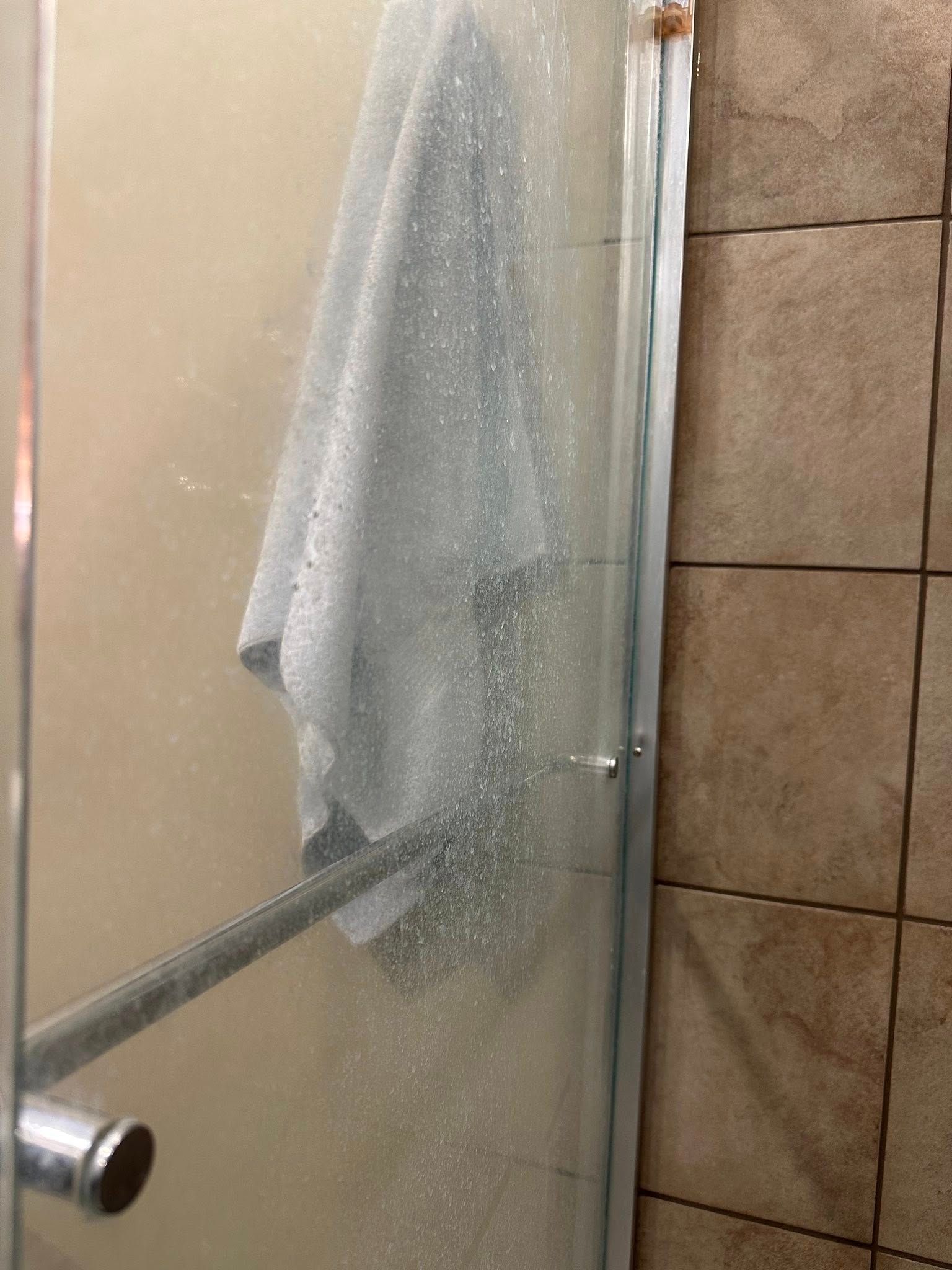 Shower door with a towel hanging inside; door is foggy.