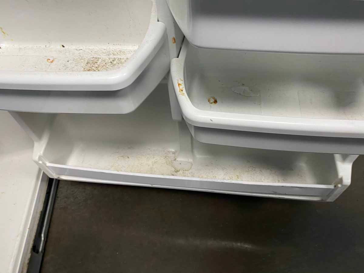 Dirty refrigerator door shelves with food debris.