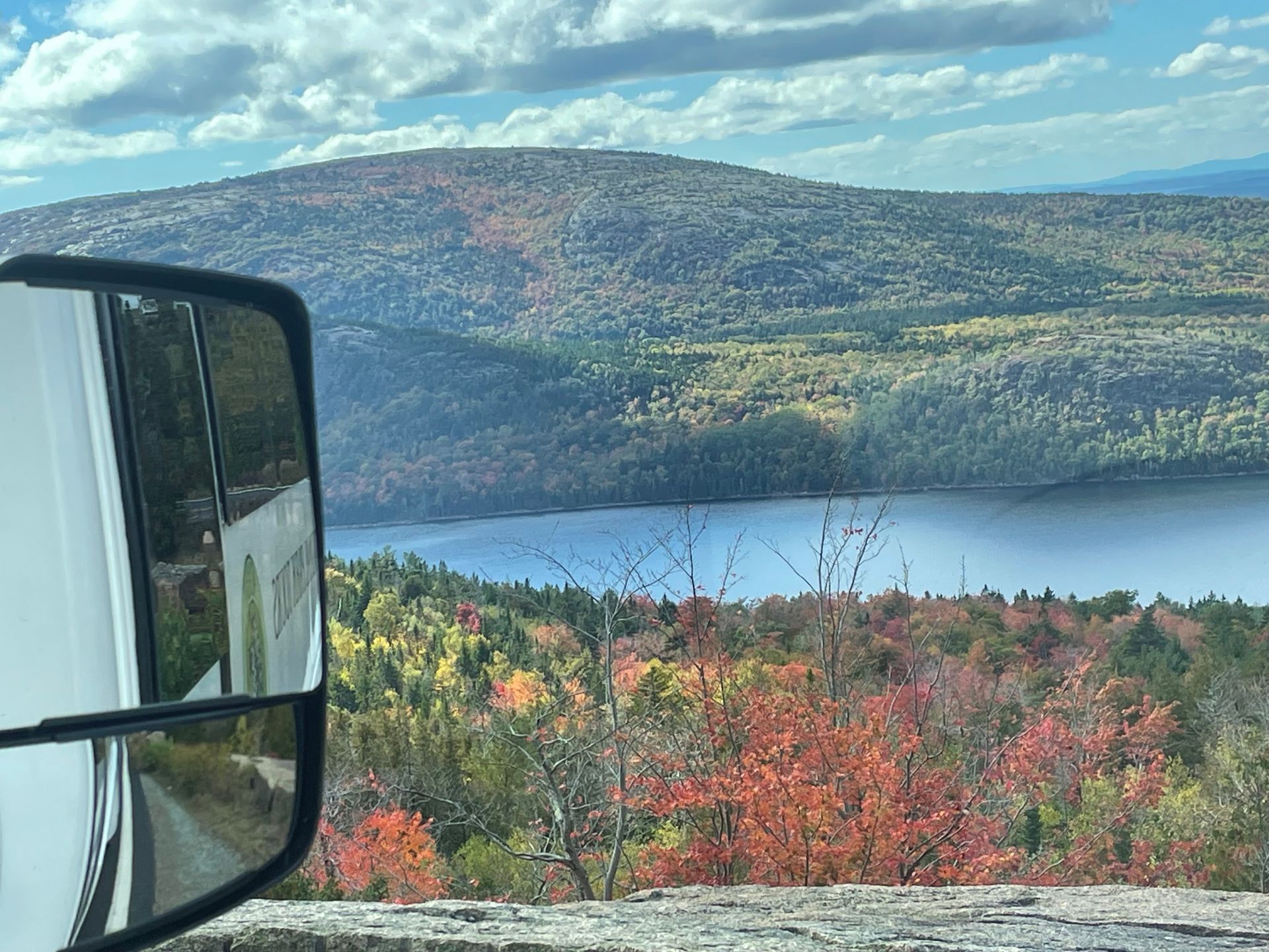 A view of a lake from the top of a mountain surrounded by trees.