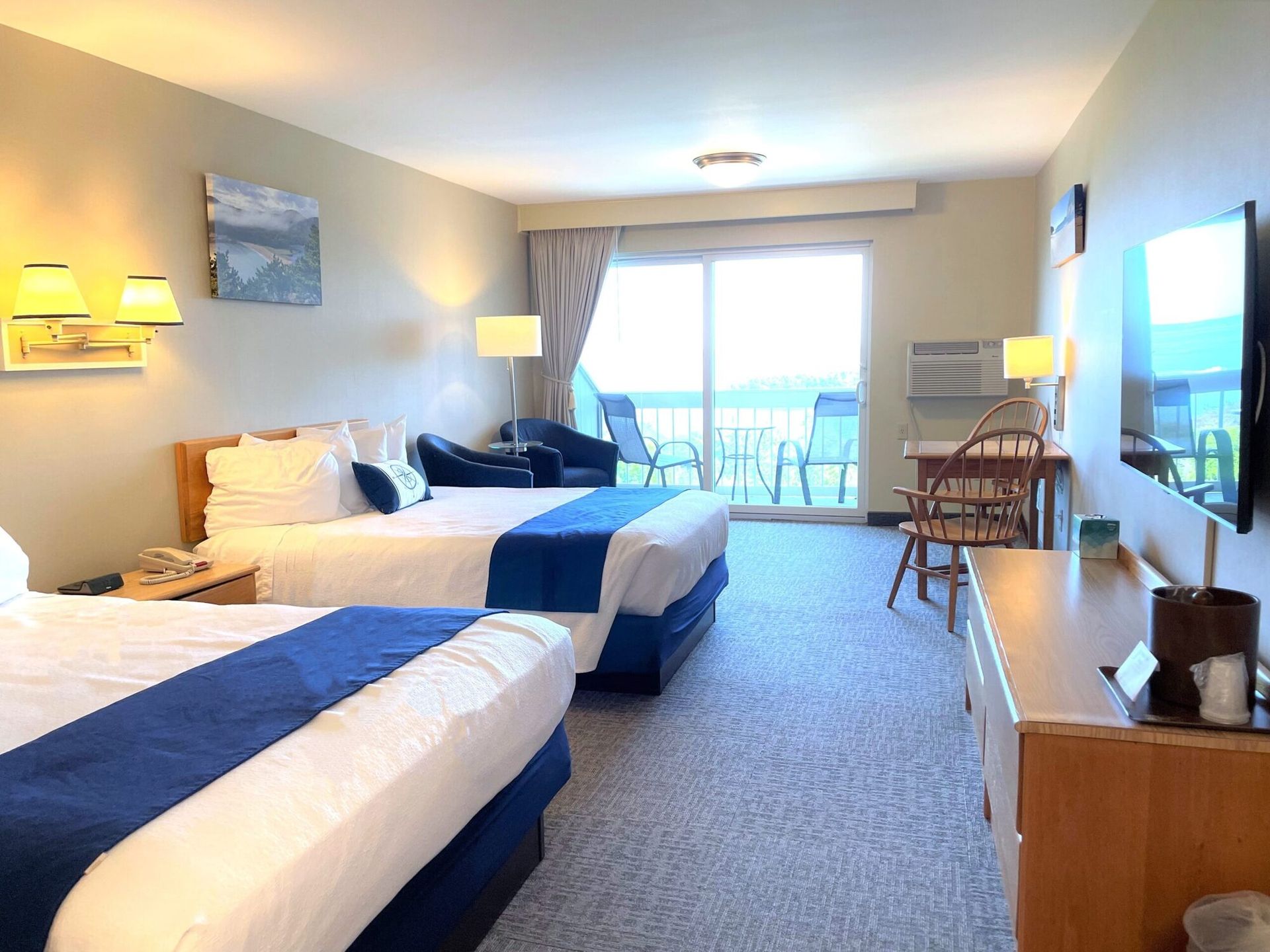 A hotel room with two beds , a desk , a television and a balcony.
