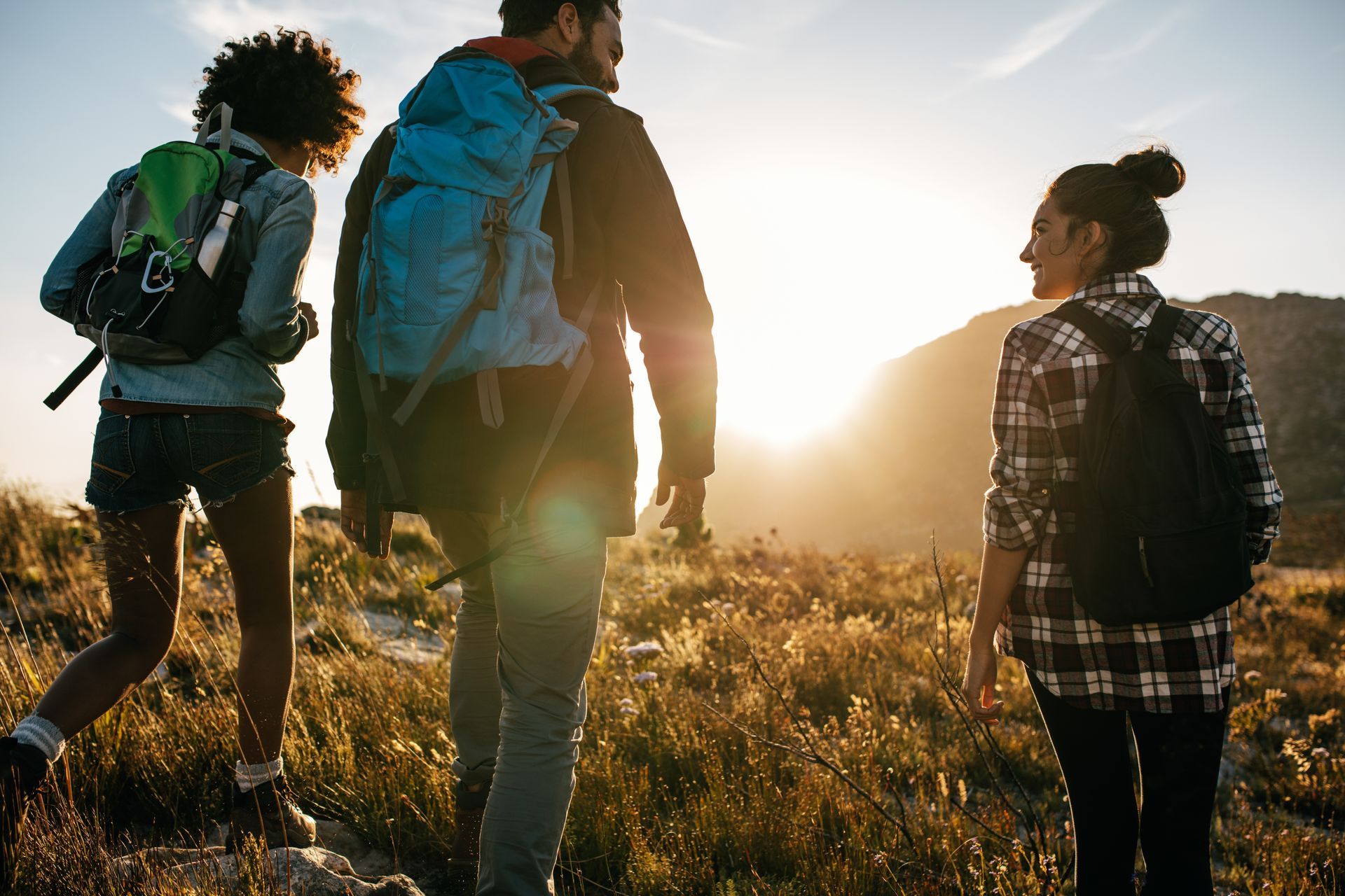 A group of people with backpacks are walking through a field.