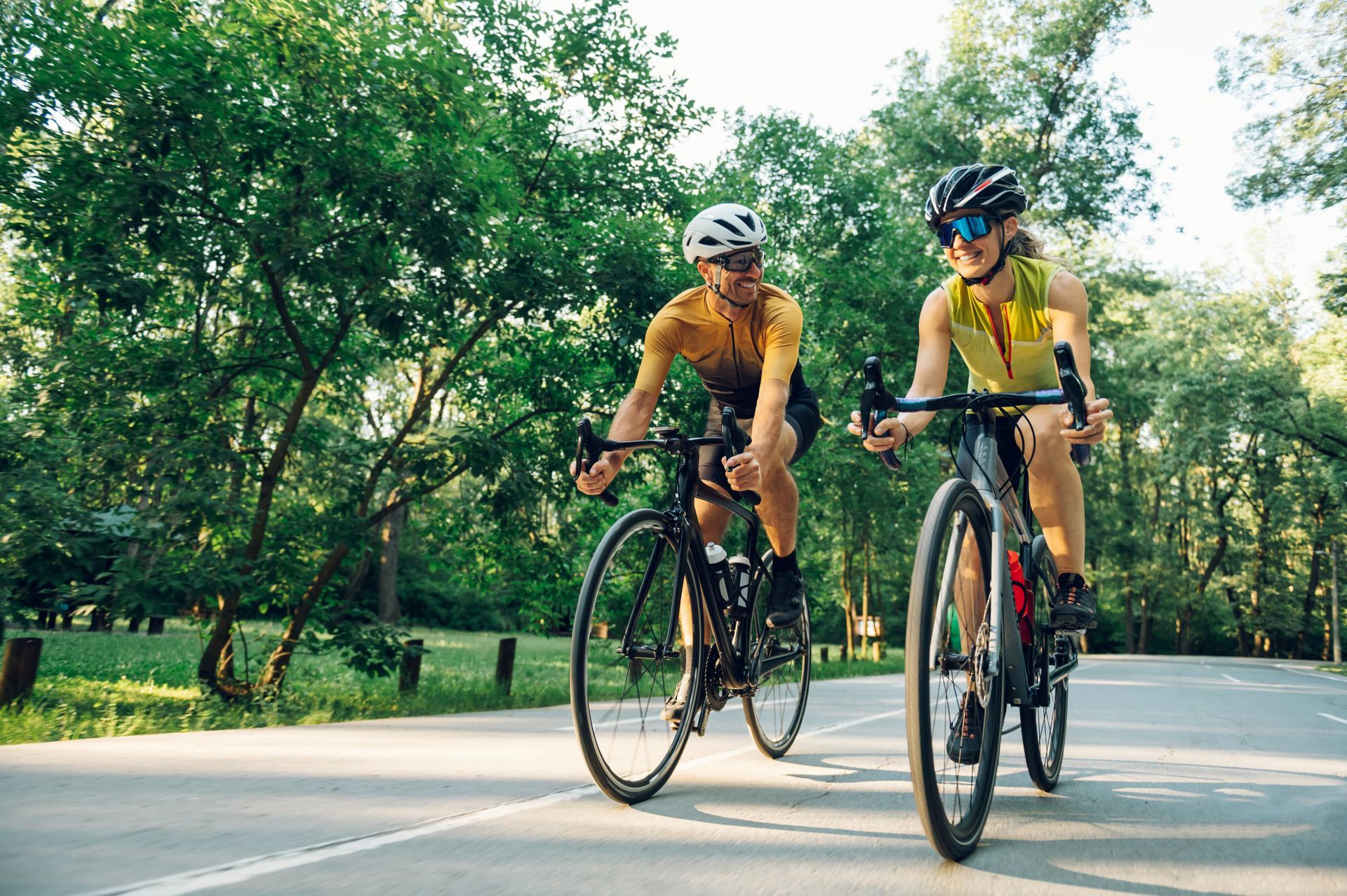 A man and a woman are riding bicycles down a road.