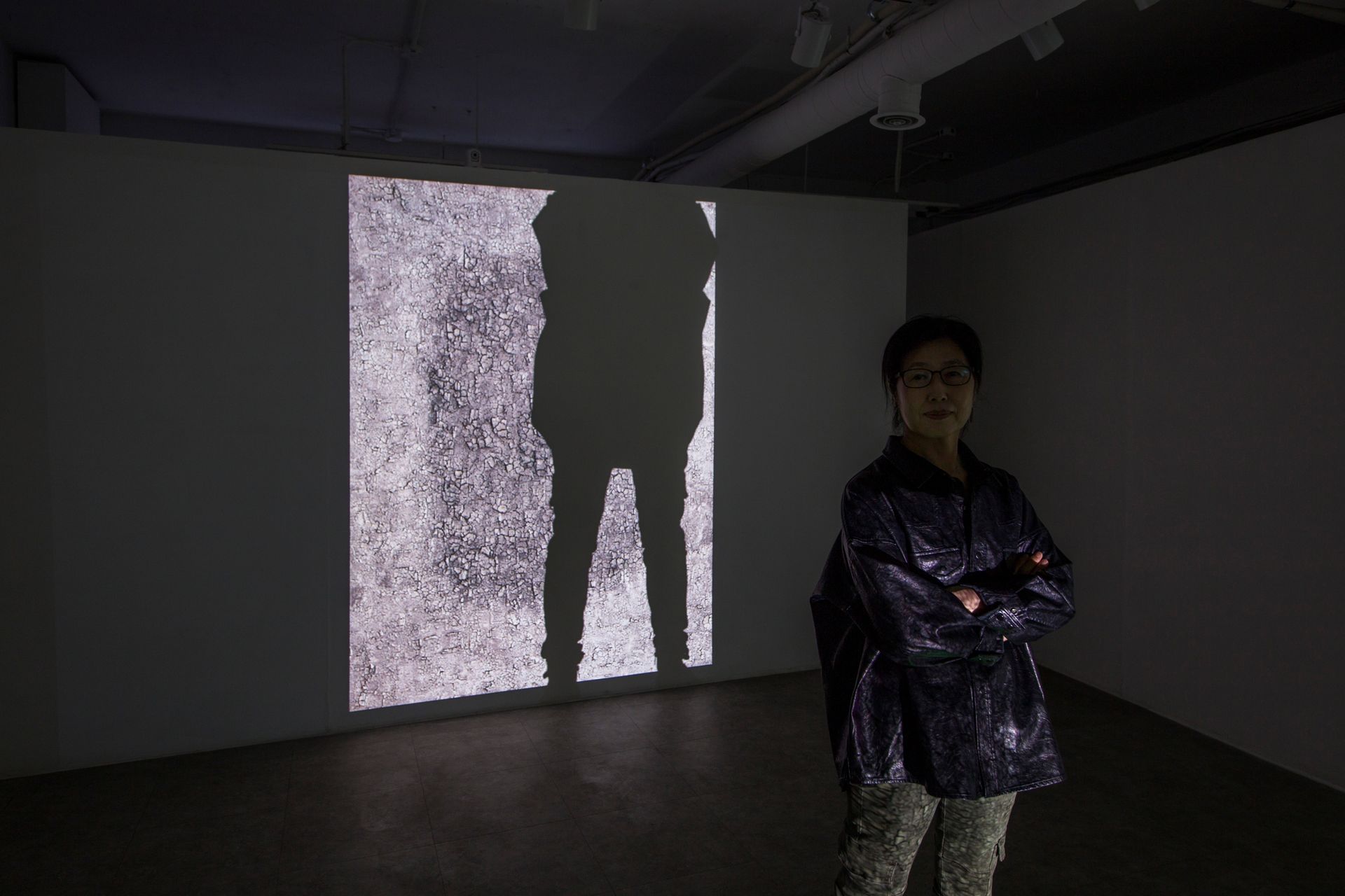artist youngsoo stella kim  is standing in front of a projection of her digital art. 