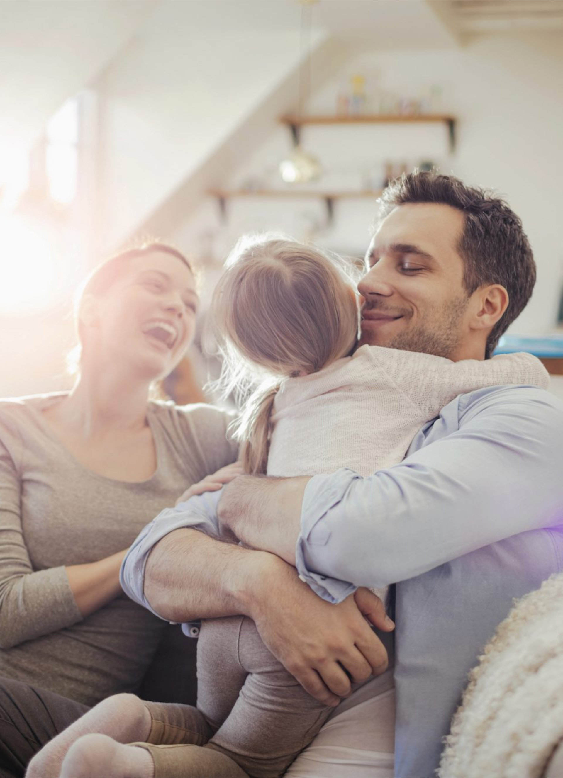 Father hugging daughter while mother sits next to them on the couch