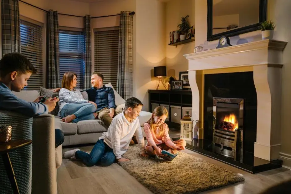A family is sitting on a couch in a living room next to a fireplace.