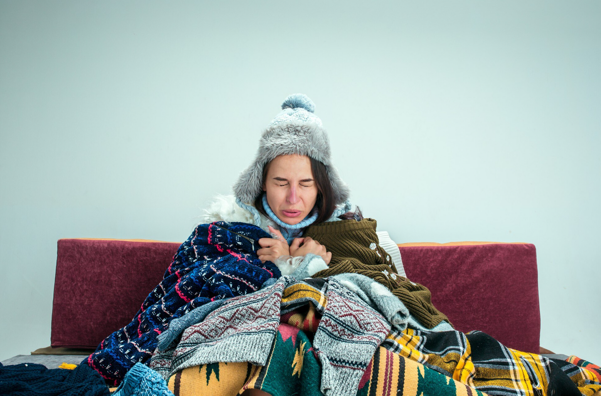 a woman is sitting on a bed wrapped in blankets and a hat .