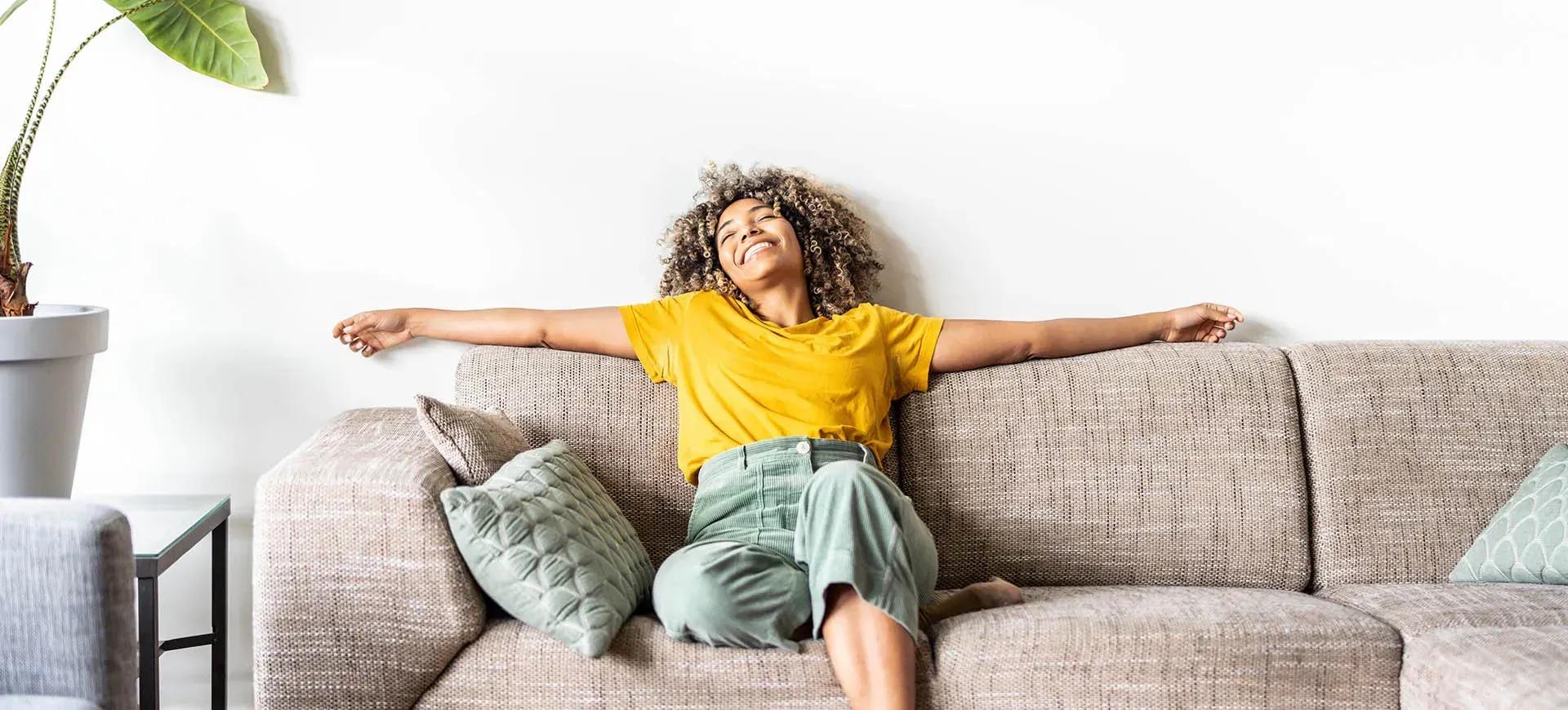 A woman is sitting on a couch with her arms outstretched.