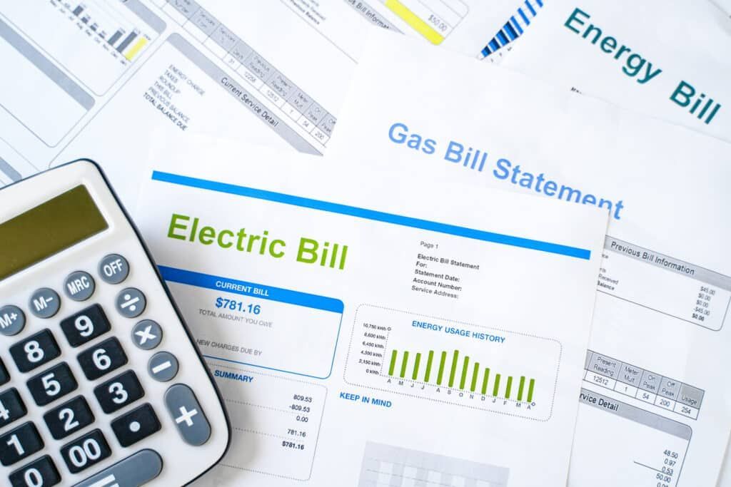 Calculator on top of utility bills for electricity, gas, and energy.