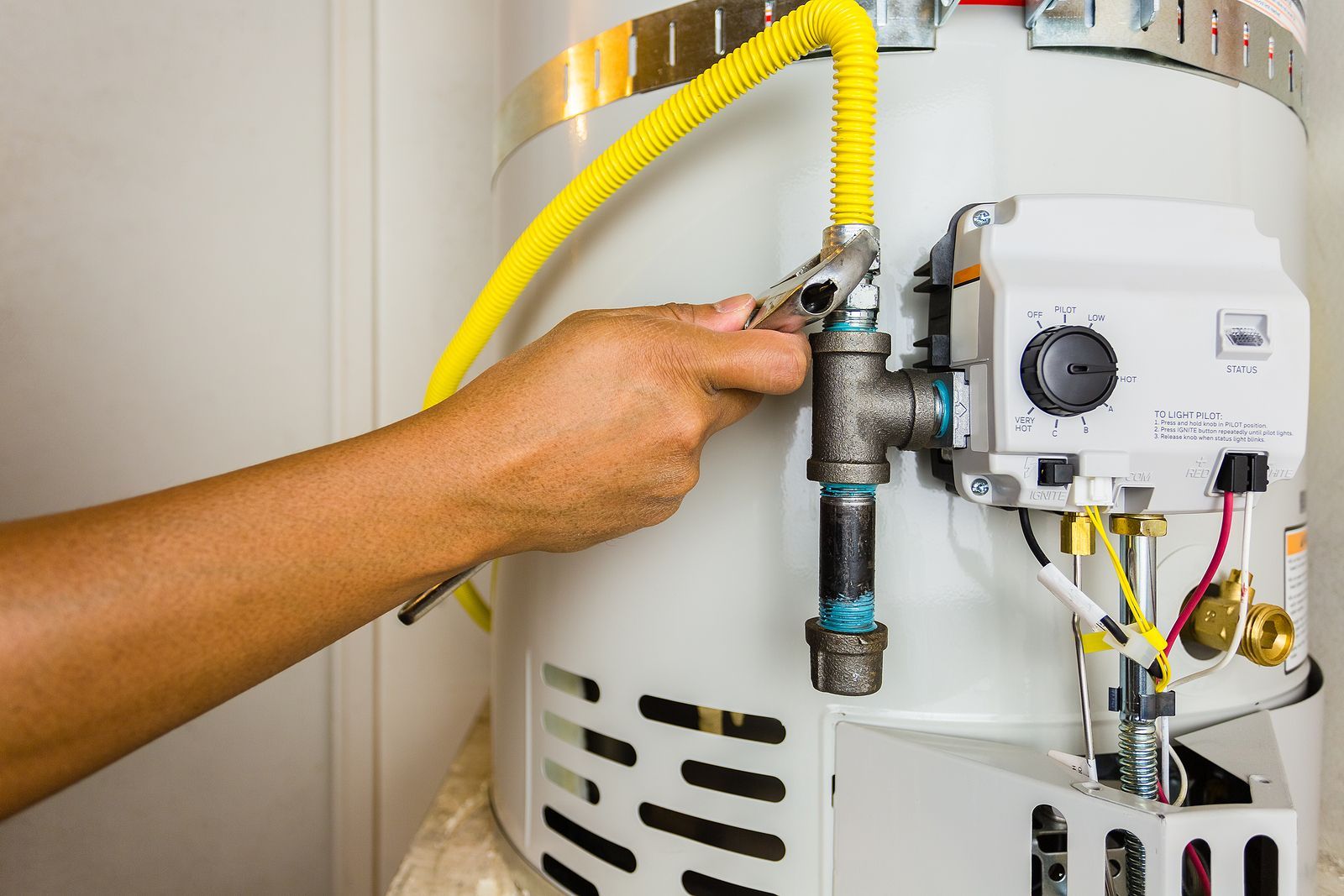 a person is fixing a water heater with a wrench .