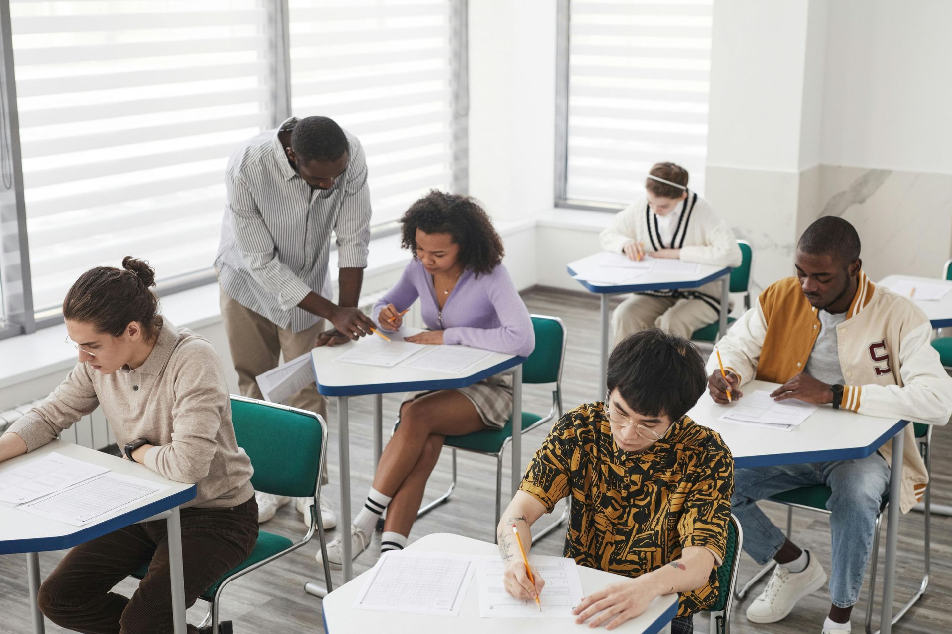 veteran Students taking a written exam in a bright classroom, seated at individual desks.