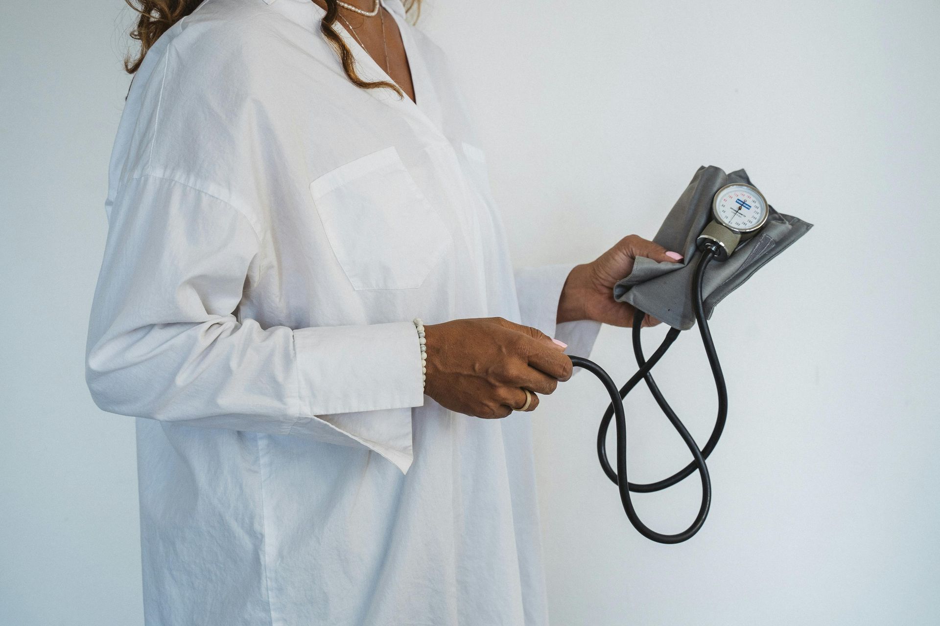 VA Doctor in white lab coat holding a blood pressure cuff against a white background