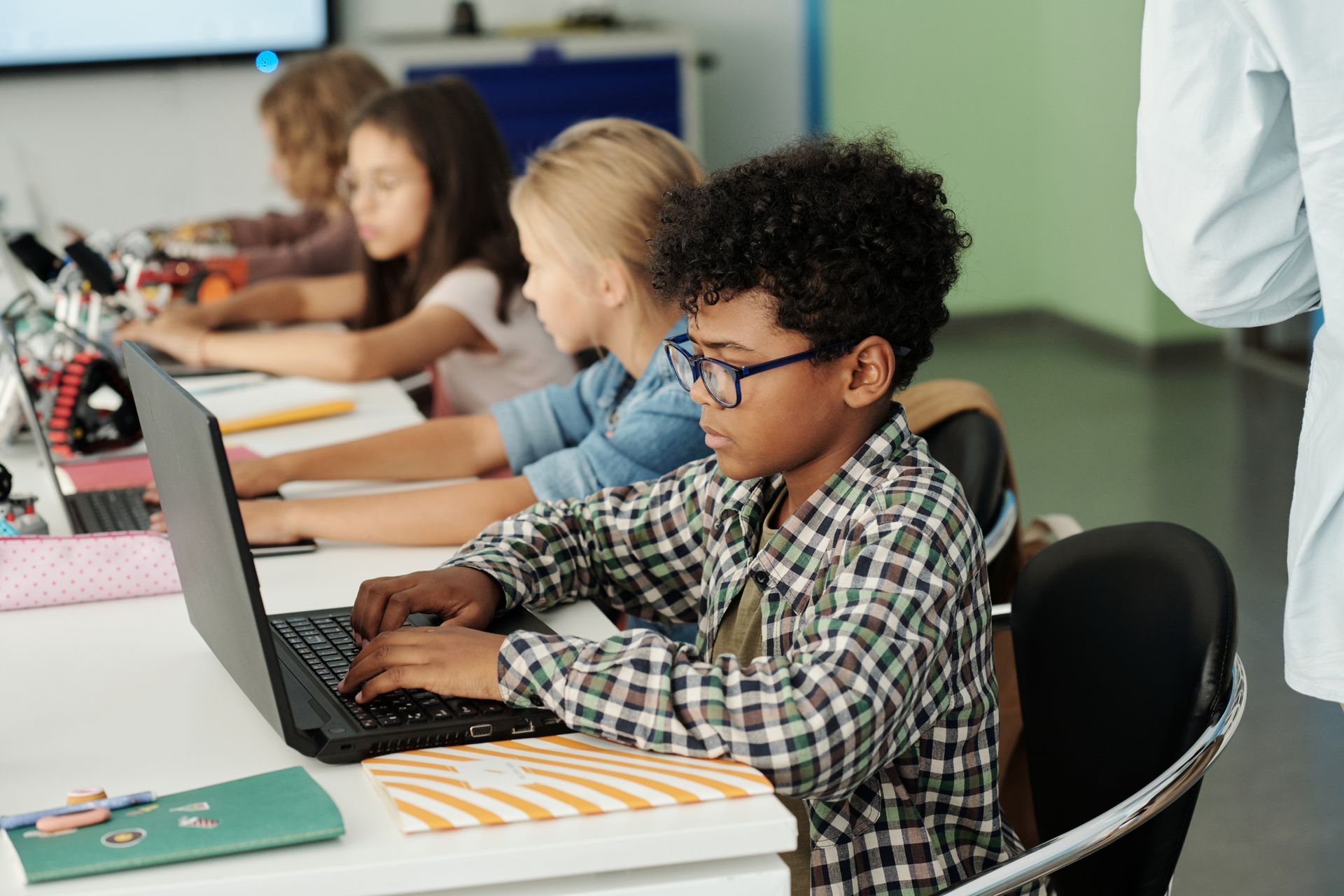 A group of children are using laptops in a classroom.