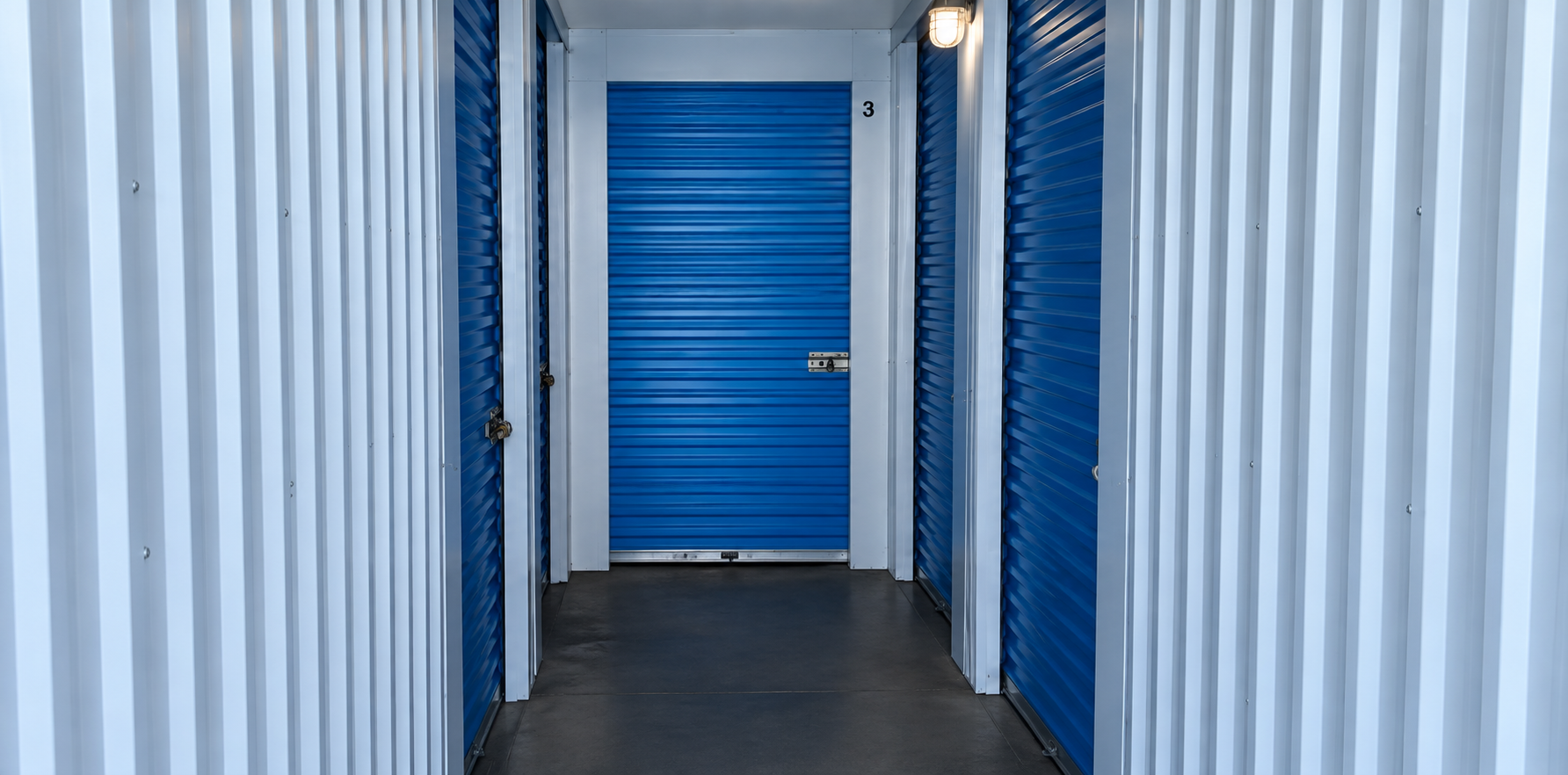 A hallway with bright blue doors leading to indoor storage units