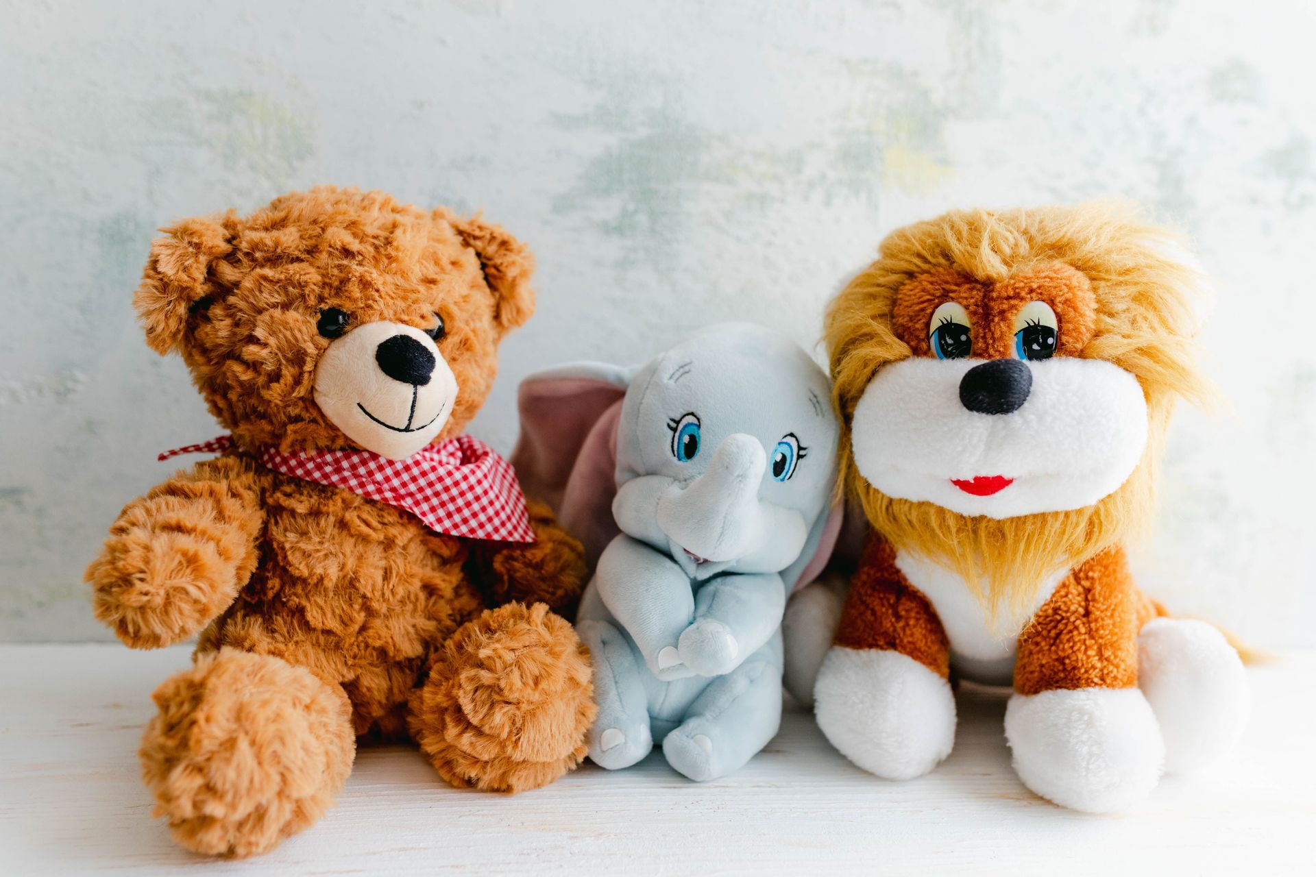 A teddy bear, a stuffed elephant, and a stuffed lion