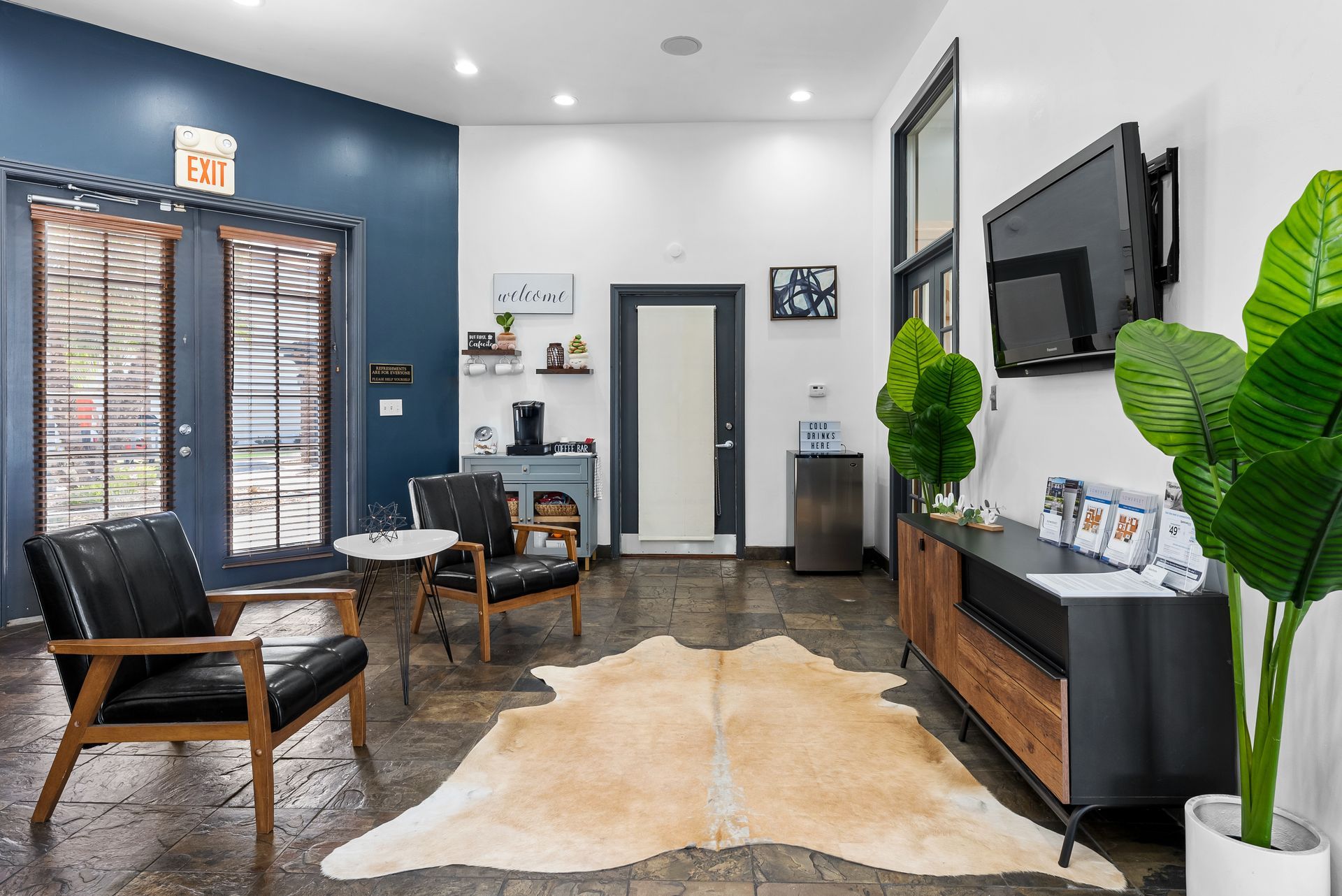 Waiting area with blue walls, black furniture, and cowhide rug.