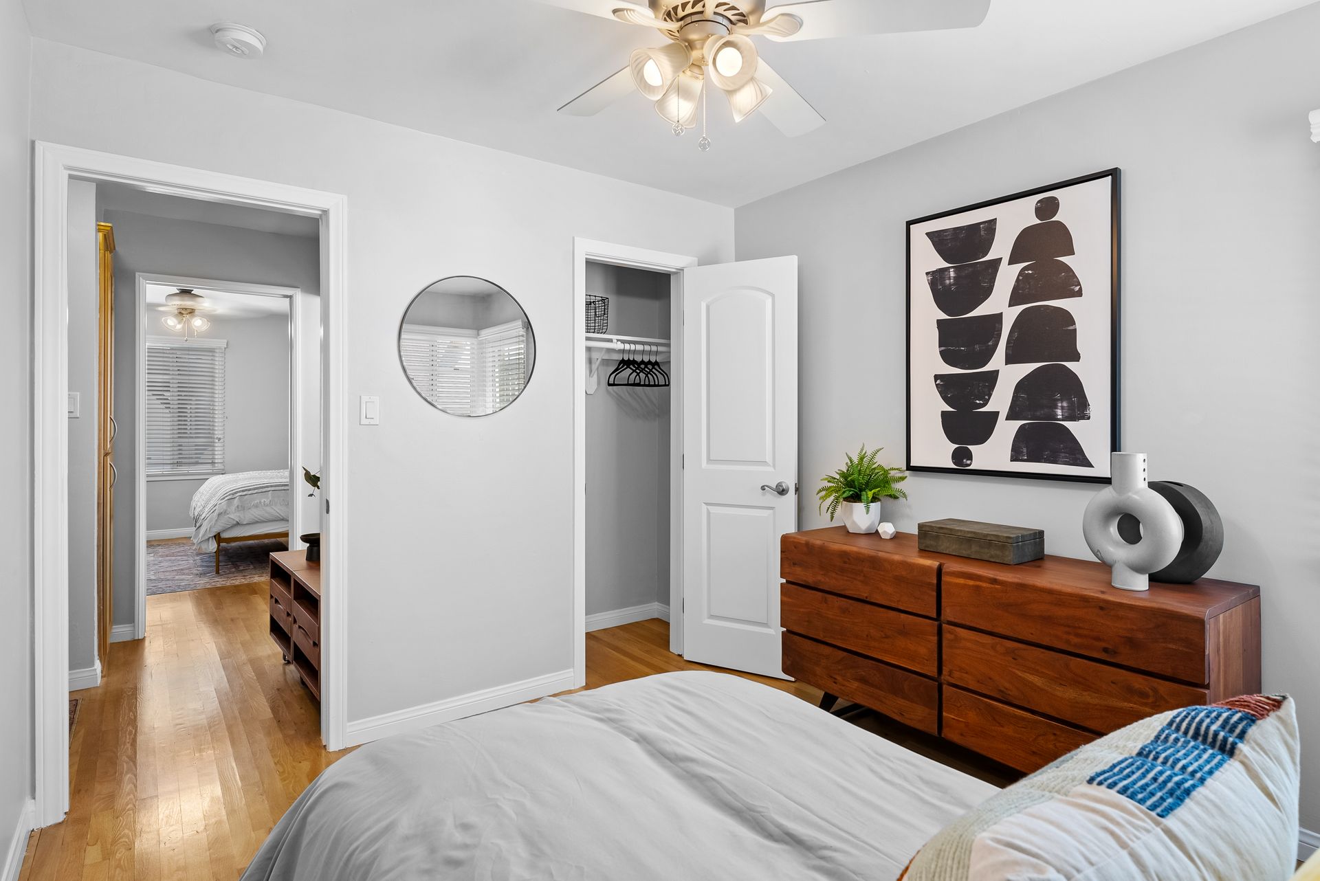 Bedroom with a dresser, art, open closet, and an open doorway to another bedroom.