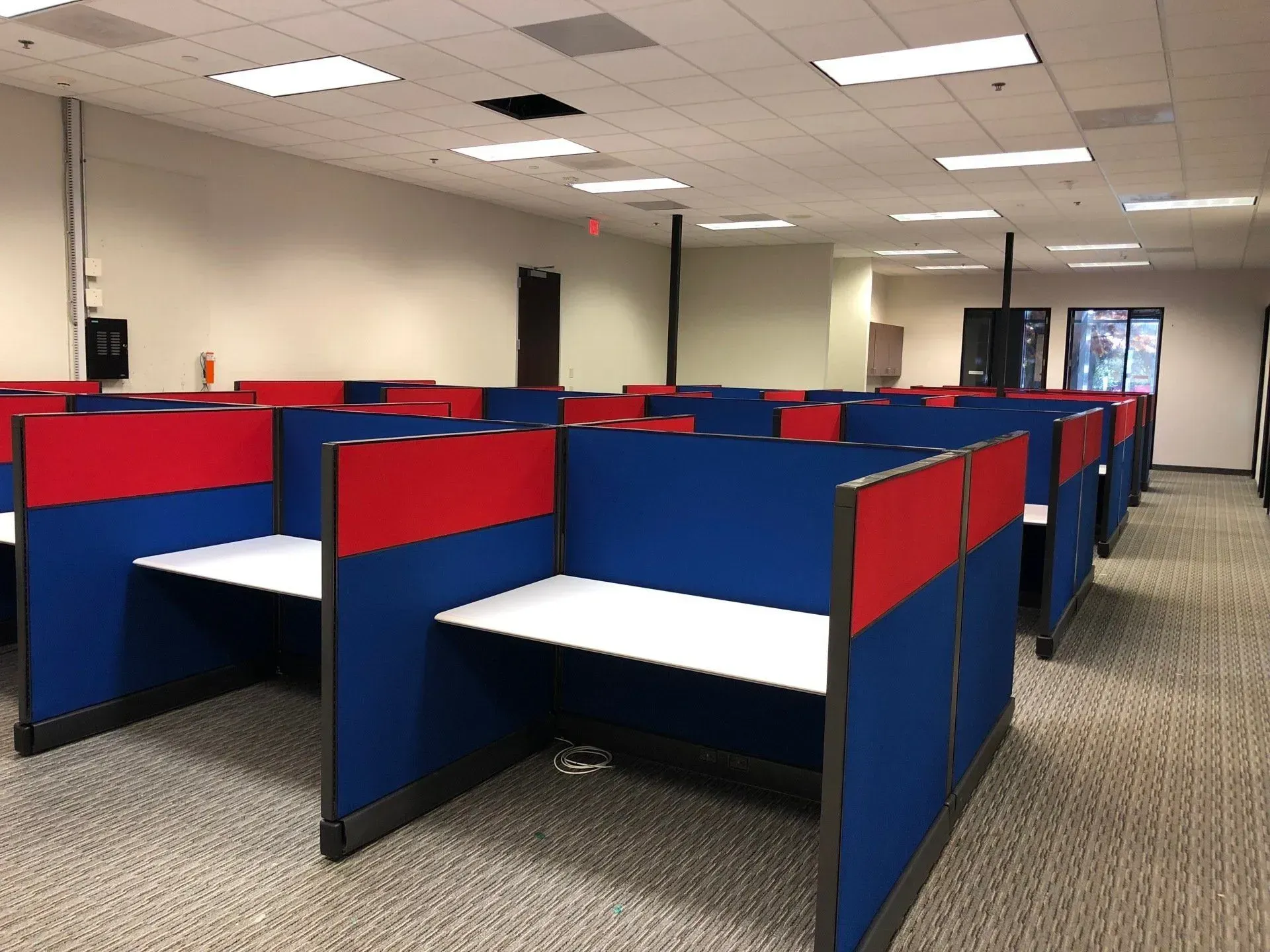 A row of blue and red cubicles in an office.
