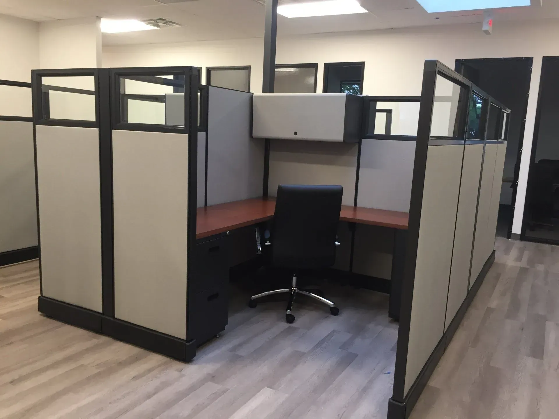 A cubicle with a chair and a desk in an office.