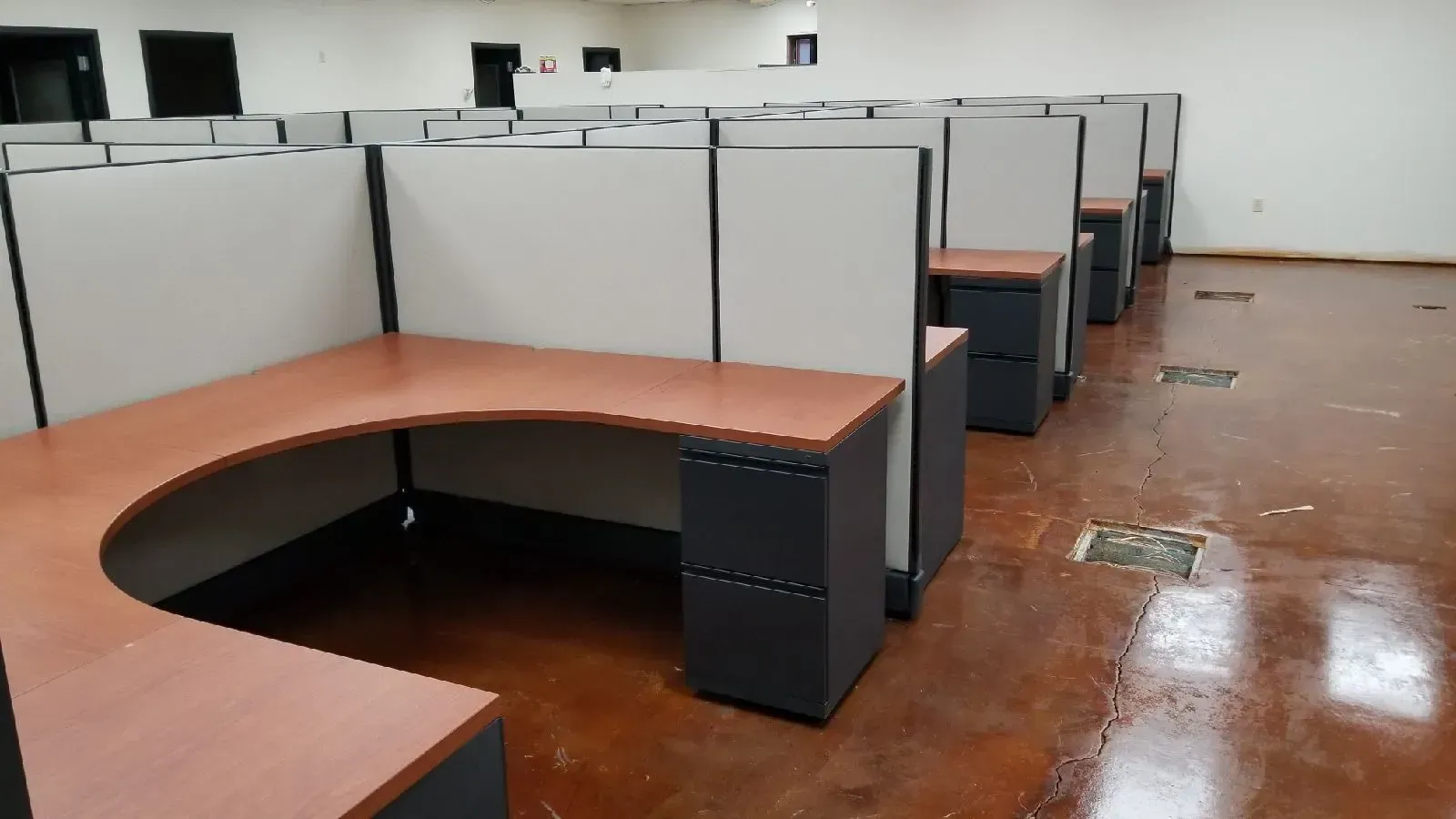 A row of cubicles in an office with a concrete floor