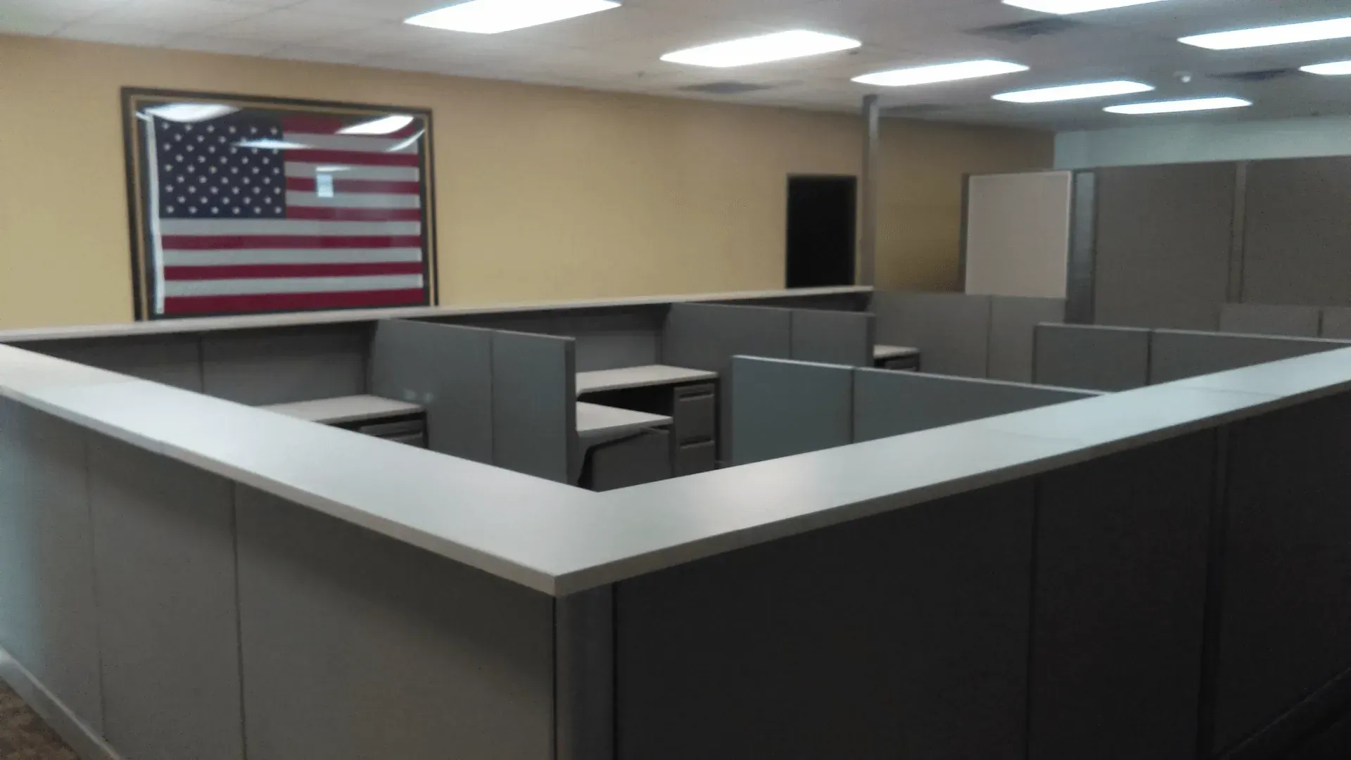 An office with cubicles and an american flag on the wall