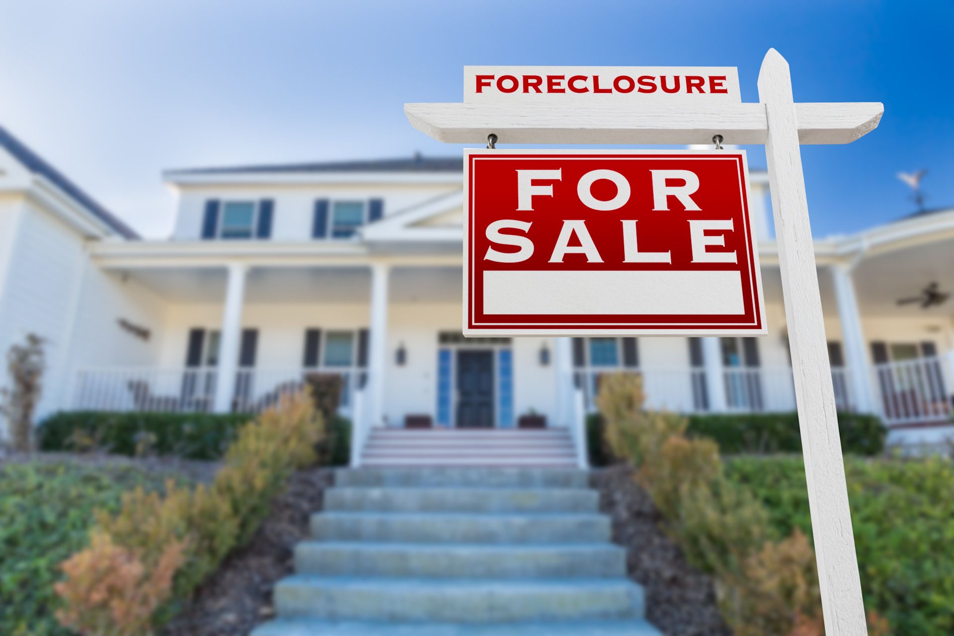 A for sale sign is in front of a white house.