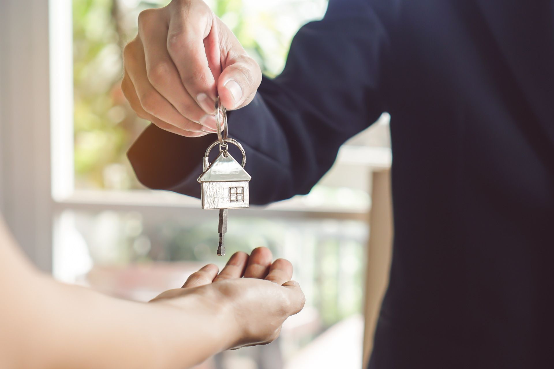 A man is handing a house key to a woman.