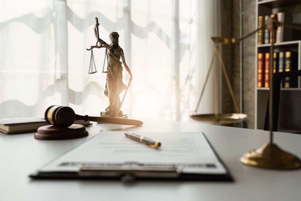 A gavel, contract, and statue of justice in the table
