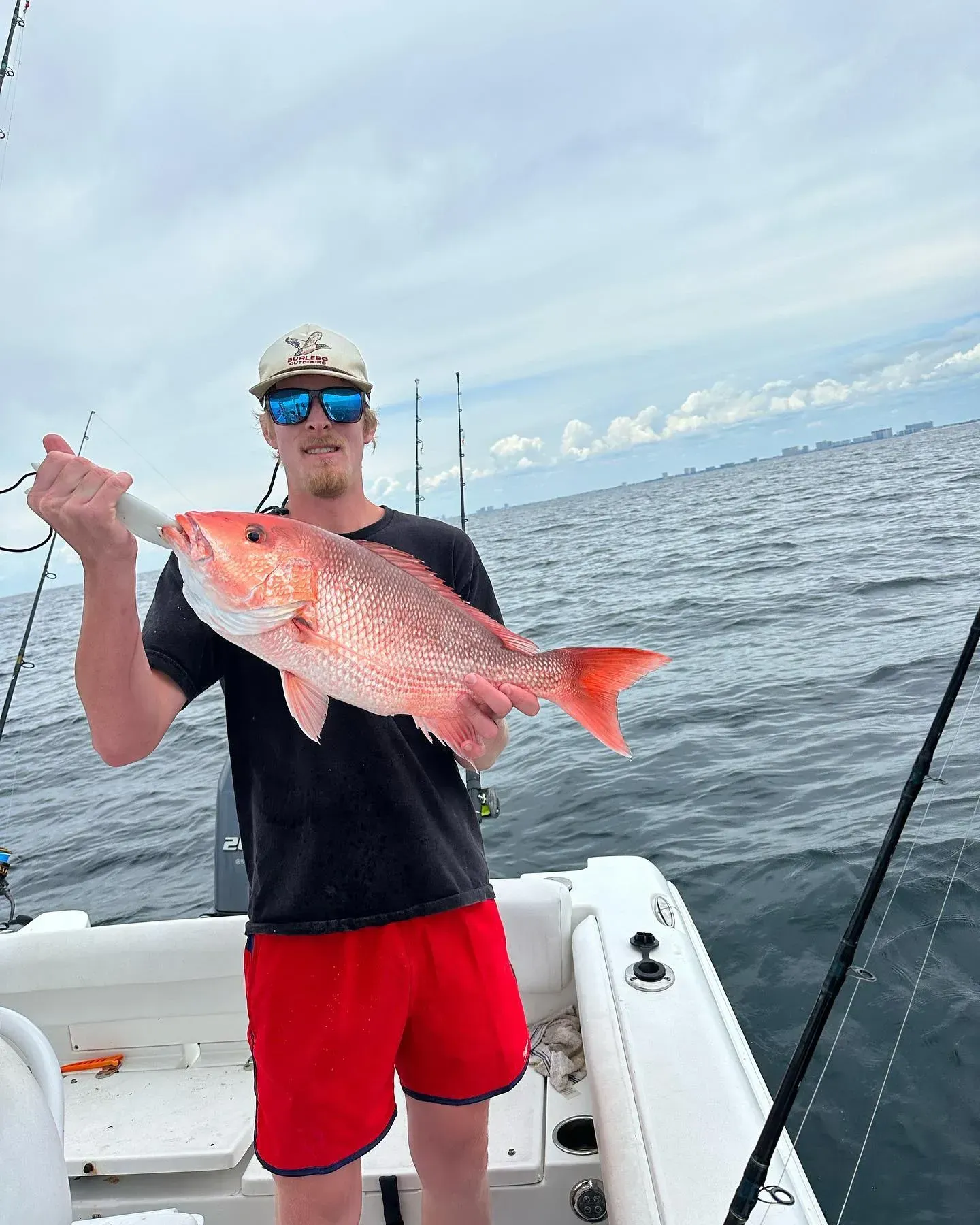 Man on a boat holding a large pink fish on a calm ocean