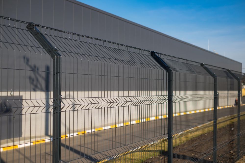 A Metal Fence is Surrounding a Large Building — SMH Valley Fencing & Maintenance In Millfield, NSW