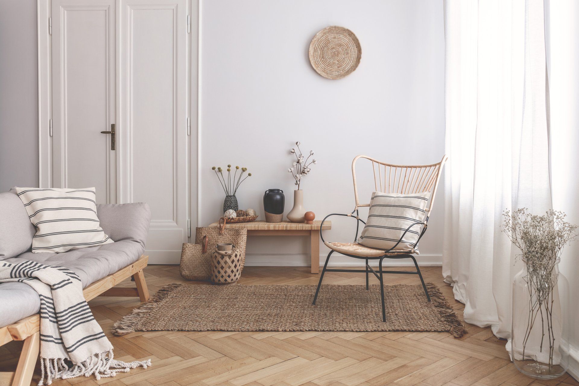 A natural styled living room with light walls, a chair, a table and a lamp.